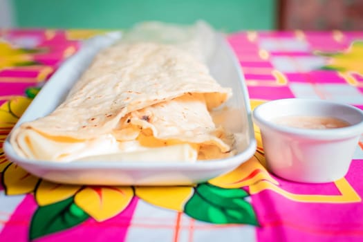 Close up of a Nicaraguan quesillo served on wooden table. Top view of Nicaraguan Quesillo on a plate served on wooden table. Delicious traditional Nicaraguan quesillo served on wooden table