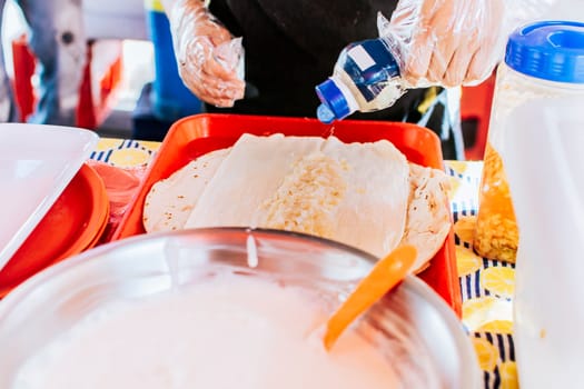 Close up of hands making a traditional quesillo with pickled onion. Preparation of Nicaraguan QUESILLO, traditional Central American food quesillo. Hands making a Nicaraguan quesillo