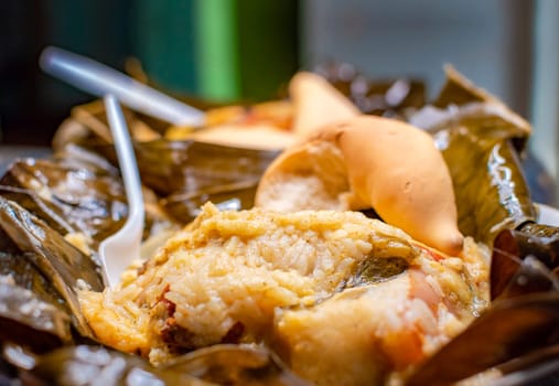 Nicaraguan Nacatamal with bread on the table, Nacatamal served with bread in a banana leaf on table. Traditional Nacatamal served in banana leaf, Traditional Venezuelan Hallaca served