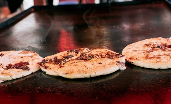 Three traditional Nicaraguan pupusas with melted grilled cheese, Traditional cheese pupusas on the grill, Close up of traditional handmade pupusas on the grill.