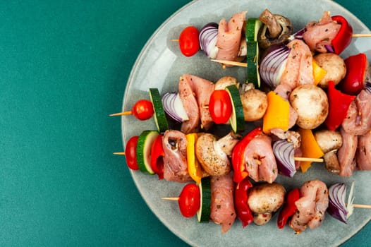 Fresh skewers with pieces of raw meat and vegetables marinated in herbs. Raw shashlik and vegetables