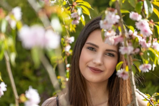 Cool brunette girl posing behind sprig of cherry blossoms.  Horizontally.