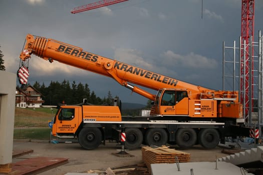by Joachim Hahne .. Feldberg (joh). A large car park is currently being built on the 1,493-metre-high Feldberg,the highest ski resort of Baden-Württemberg. This means that the decades-long period of suffering for skiers after a search for a parking space along the Bundesstraße 317 and also the motorists who use the cross-connection from the High Black Forest to the Wiesental should finally be over. .. At present,heavy construction machinery still dominates the action on the "highest"". However,the first contours of the new car park,which has been controversial for many years,are already clearly visible. .. According to Mayor Stefan Wirbser,who is also chairman of the Feldberg Lift Association,the 1209 pitches will be available to winter sports enthusiasts as early as the opening of the new ski season 2015/16. The cost of the car park is about 13 million euros... A heavy construction crane lifts the prefabricated part for the new Car Park Feldberg am Seebuck"
