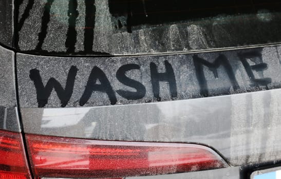 A dirty black car says wash me