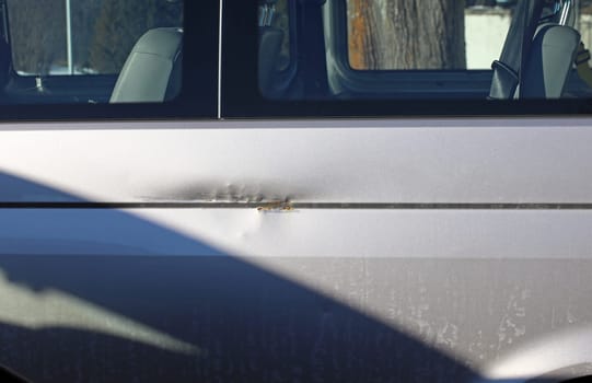 A dent and rust on the paint of a silver car