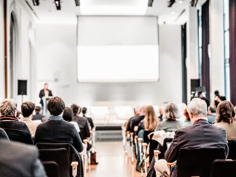 Speaker giving a talk in conference hall at business event. Rear view of unrecognizable people in audience at the conference hall. Business and entrepreneurship concept
