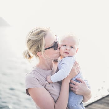 Tender woman caressing her little baby boy infant child outdoors. Mother's unconditional love for her child.