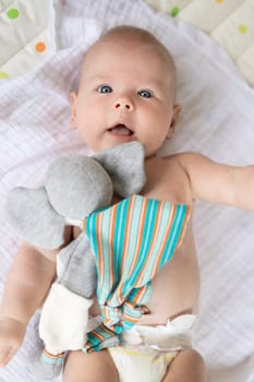 Cute baby boy playing with hanging toys arch on mat at home Baby activity and play center for early infant development. Baby playing at home.