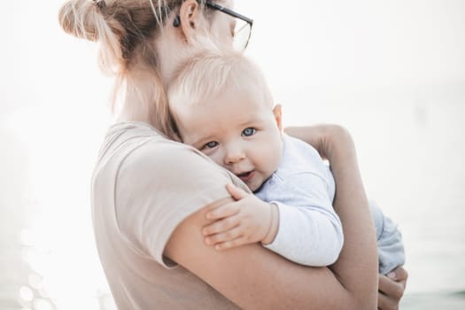 Tender woman caressing her little baby boy infant child outdoors. Mother's unconditional love for her child.