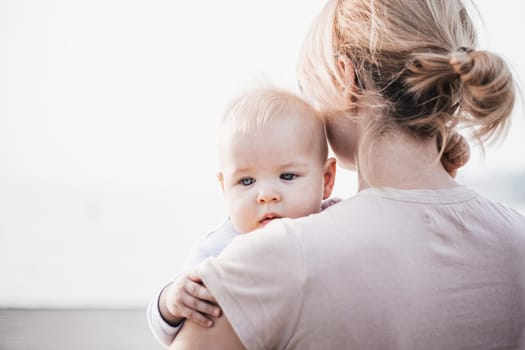 Tender woman caressing her little baby boy infant child outdoors. Mother's unconditional love for her child.