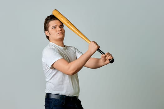 A man with a bat in his hands swings on a gray background. High quality photo