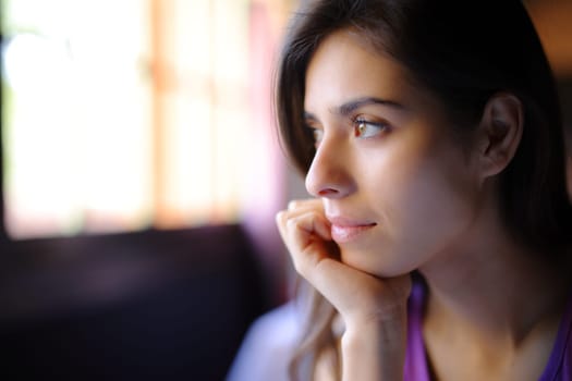 Beautiful woman relaxing looking through a window in a house interior