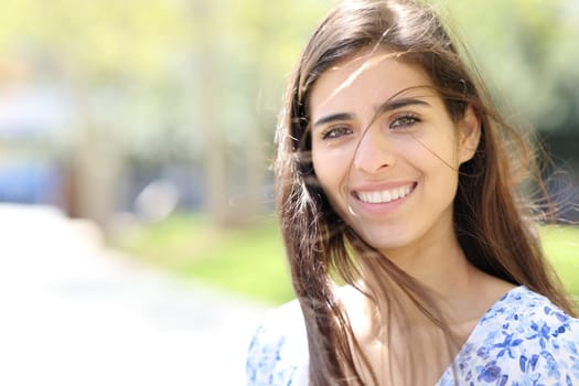 Happy woman with tousled hair looks at you in the street