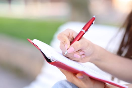 Close up of a hand wrting in paper agenda in the street
