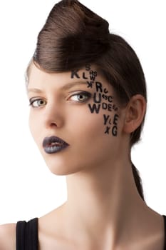 very cute young girl with letter and number painted on her face and a nice creative hair style, she is turned of three quarters at right and looks in to the lens
