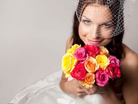 pretty brunette wearing wedding dress on light background