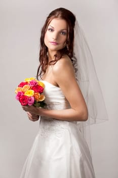 pretty brunette wearing wedding dress on light background