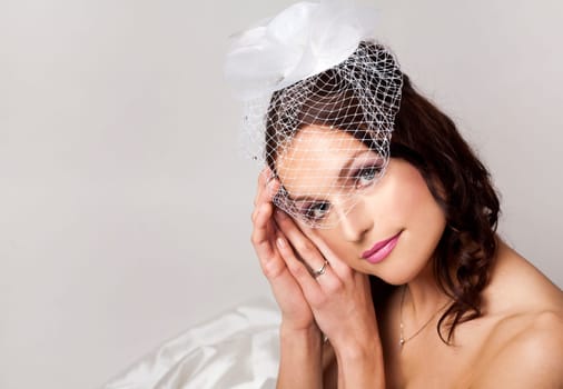 pretty brunette wearing wedding dress on light background