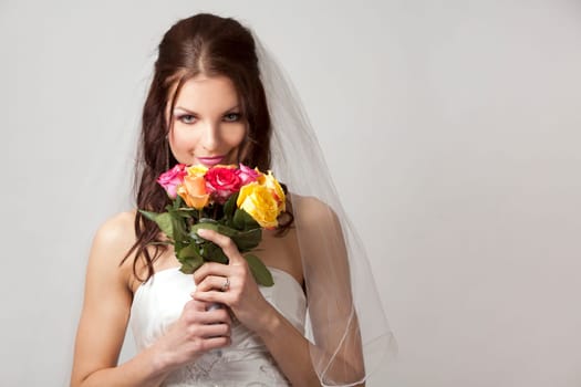 pretty brunette wearing wedding dress on light background