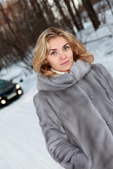 Young woman near the car in Winter forest