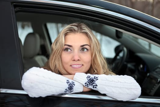 Young woman in the car. Winter forest