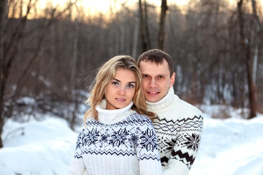 Happy pair in winter forest dressed in sweater