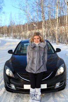 Young woman near the car in Winter forest
