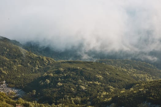 Mountain landscape. Scenic view of mountain peaks, slopes, hills and valleys covered with foggy slopes and valleys. Panoramic view. Natural scenery. Beautiful background