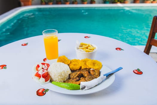 Delicious breakfast near a crystal clear pool. Traditional breakfast with orange juice served near a swimming pool