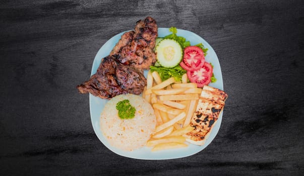 Plate of roasted chicken with rice and french fries on wooden table, Top view of plate of roasted chicken with rice and french fries served, Typical Nicaraguan food roasted chicken with french fries