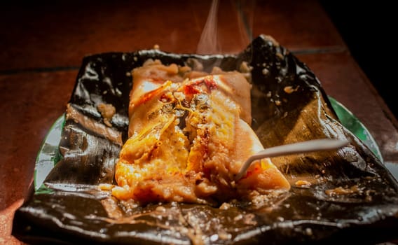 Traditional Nacatamal served in banana leaf, Close up of Nicaraguan Nacatamal ready to eat, Typical Nicaraguan Nacatamal freshly made served on the table. Homemade Nicaraguan Nacatamal