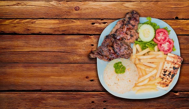 Roasted chicken dish with gallo pinto and pico de gallo on wooden table, Top view of roasted chicken dish with rice t french fries served on wooden background, Concept of typical Nicaraguan food