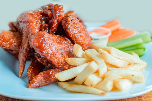 Plate of barbecue wings and fries with ranch sauce, Close up of plate of hot wings and fries served on the table. National typical food concept