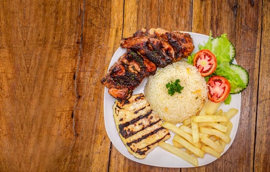 Top view of plate of fresh Pork rib served on the table. Pork rib with rice, fried cheese and salad served on the table, Close up of Pork rib with salad and French fries served on wooden table