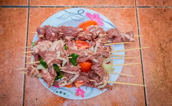 Raw beef skewers on a plate. Preparation of raw beef skewers. Fresh and raw beef skewers on a plate. Close up of raw beef meat skewers with ingredients