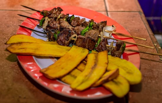 Roast beef skewers served on a silver, roast beef on skewers served with fried plantain