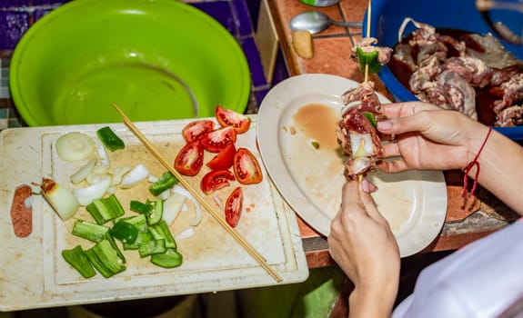 A person preparing roast beef skewers, close up of hands preparing meat skewers
