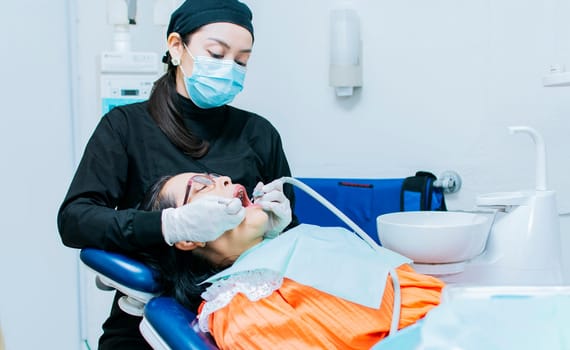 The stomatologist cleaning a patient's teeth, a dentist cleaning a patient's mouth, a dentist cleaning a patient's caries, a dentist cleaning a patient's mouth