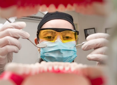 A dentist cleaning a mouth inside view, Inside view of a mouth checked by a dentist, a female dentist checking a patient. dentist checking a mouth, a dentist cleaning teeth.