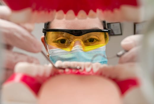 A dentist cleaning a mouth inside view, Inside view of a mouth checked by a dentist, a female dentist checking a patient. dentist checking a mouth, a dentist cleaning teeth.