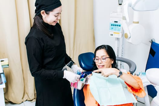 Patient with dentist choosing dental braces, Dentist with patient choosing metal braces, Patient with dentist choosing rubber band