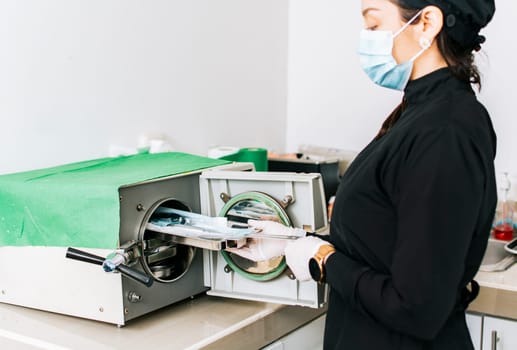 Dentist with a dental sterilizer, A dentist sterilizing his tools, A dentist with a dental autoclave, Close up of a dentist with a steam sterilizer
