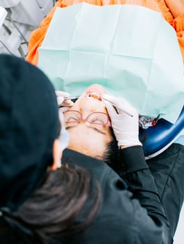 View back of dentist with patient   Woman dentist doing endodontics to woman patient  Dentist examining mouth to patient  Dentist performing stomatology