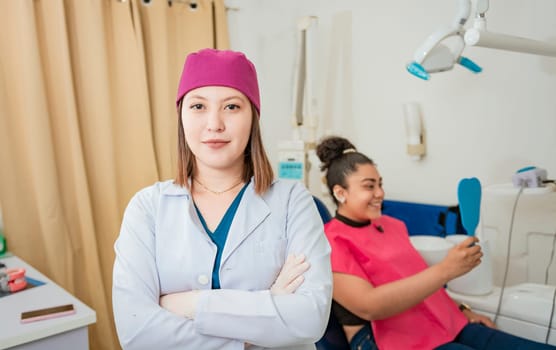 Portrait of young female dentist in modern dental clinic. Portrait of dentist crossing arms with patient, Smiling female dentist in clinic, Close up of dentist with her arms crossed