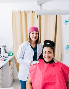 Portrait of dentist with patient smiling at camera in office, Female dentist with satisfied patient smiling at camera, Female dentist with patient smiling friendly