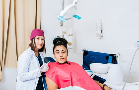 Portrait of young dentist with female patient in medical office, Female dentist with female patient looking at camera, Professional dentist with female patient in office.