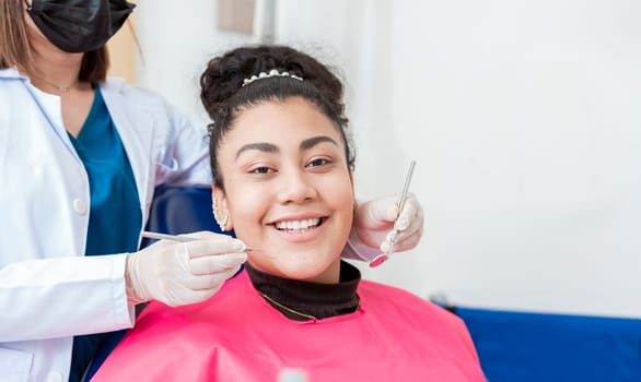Dentist doctor examining mouth to female patient looking at camera lying on chair, Female dentist with probe and dental mirror examining mouth to lying patient. Health and dental care concept