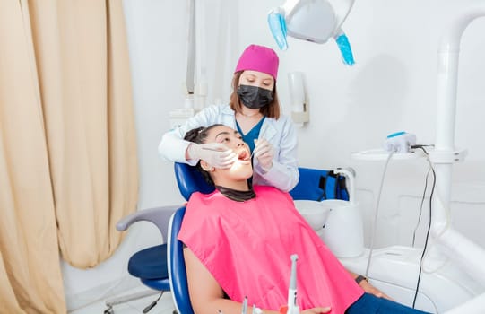 Female dentist with probe and dental mirror examining mouth to lying patient. Health and dental care concept, Dentist doctor examining mouth to female patient lying on chair