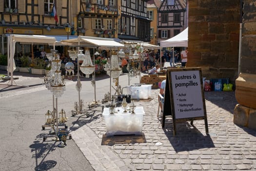 Flea market with a stand for chandeliers and lamps in the old town of Colmar in France