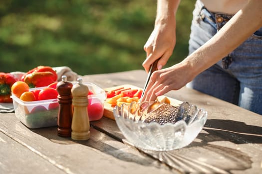 Closeup view of female hands cutting tomatoes for outdoor at picnic